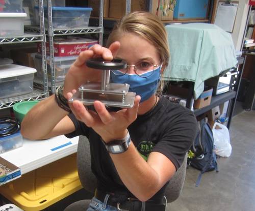 Figure 1. Stony Brook University PhD candidate, Ashley Nicoll, assembles the interior mount for a GoPro Hero/CamDo Blink controller time lapse underwater camera. The springs are used to gently press the camera against the interior face of the acrylic viewport. Read about Ashley’s MS project in Lander Lab #2, MTR, Vol. 65, #3, March/April 2022. (Photo by Kevin Hardy, Global Ocean Design.)